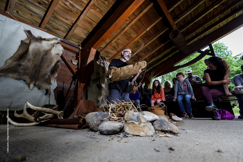 Famille découvrant une reconstitution au Parc de la Préhistoire de Tarascon-sur-Ariège